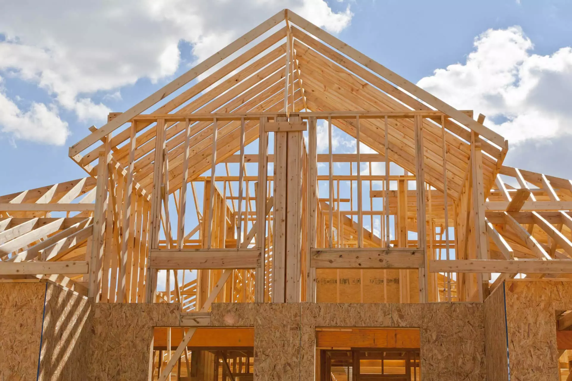 New residential construction home framing against a blue sky